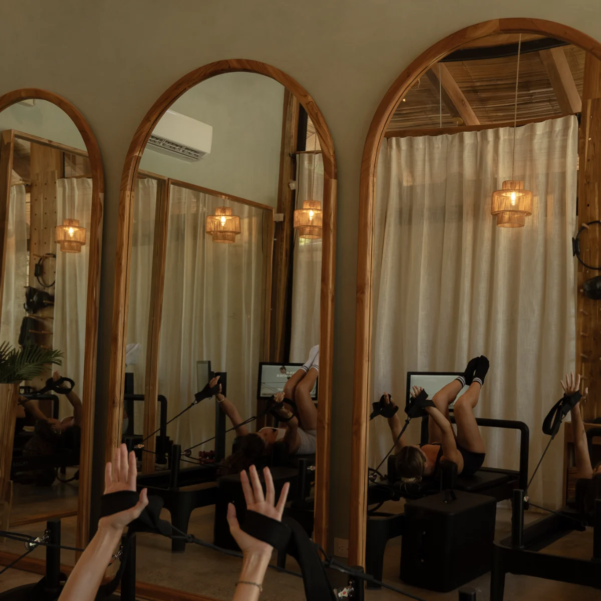 Arched mirrors and rattan lanterns in the reformer pilates studio, Santa Teresa, Costa Rica